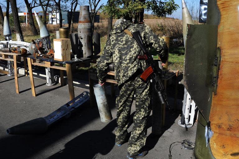 A pro-Russian separatist soldier looks at one of the rocket exposed by separatist militaries at the Makivvka checkpoint on the outskirts of Donetsk, on October 12, 2014