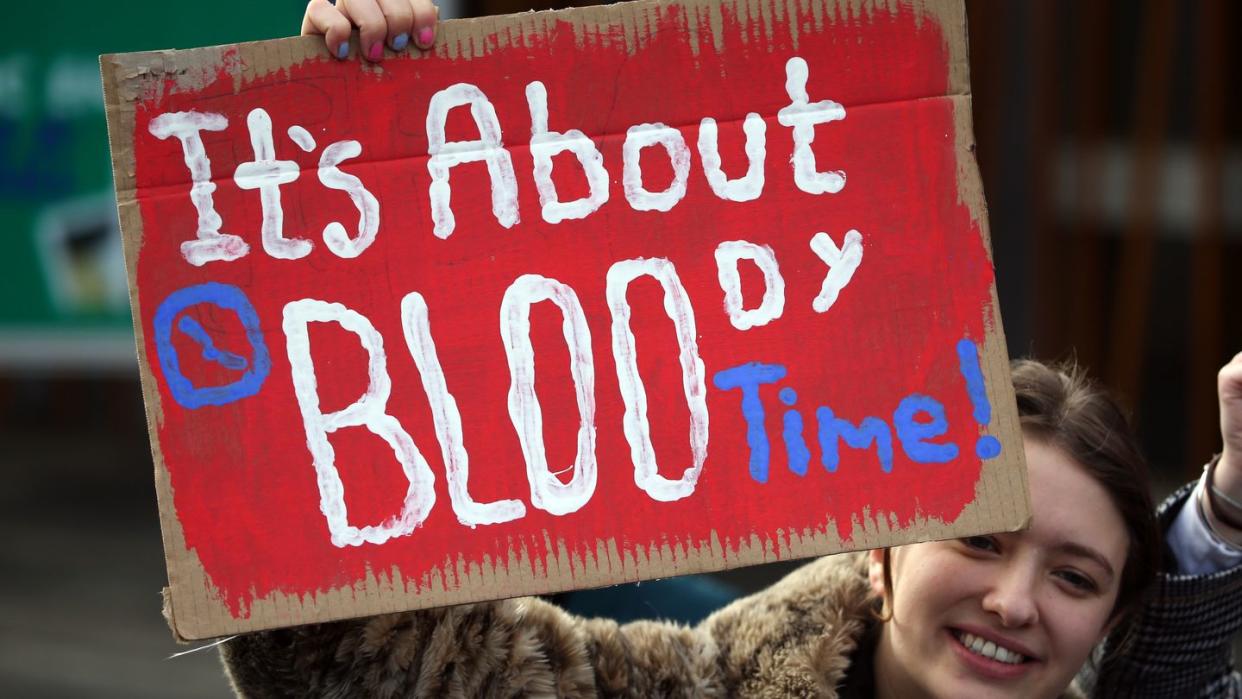 Eine Frau in Edinburgh hält bei einer Kundgebung ein Schild mit der Aufschrift "It's about bloody time!" (dt. Es ist verdammt noch mal an der Zeit) hoch.