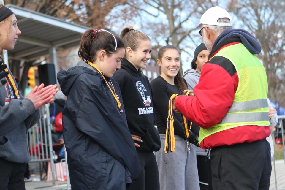 Cornwall's Karrie Baloga (center, Dragons hoodie) talks to a race official with a fellow qualifier before he presents Baloga with her fifth-place medal.