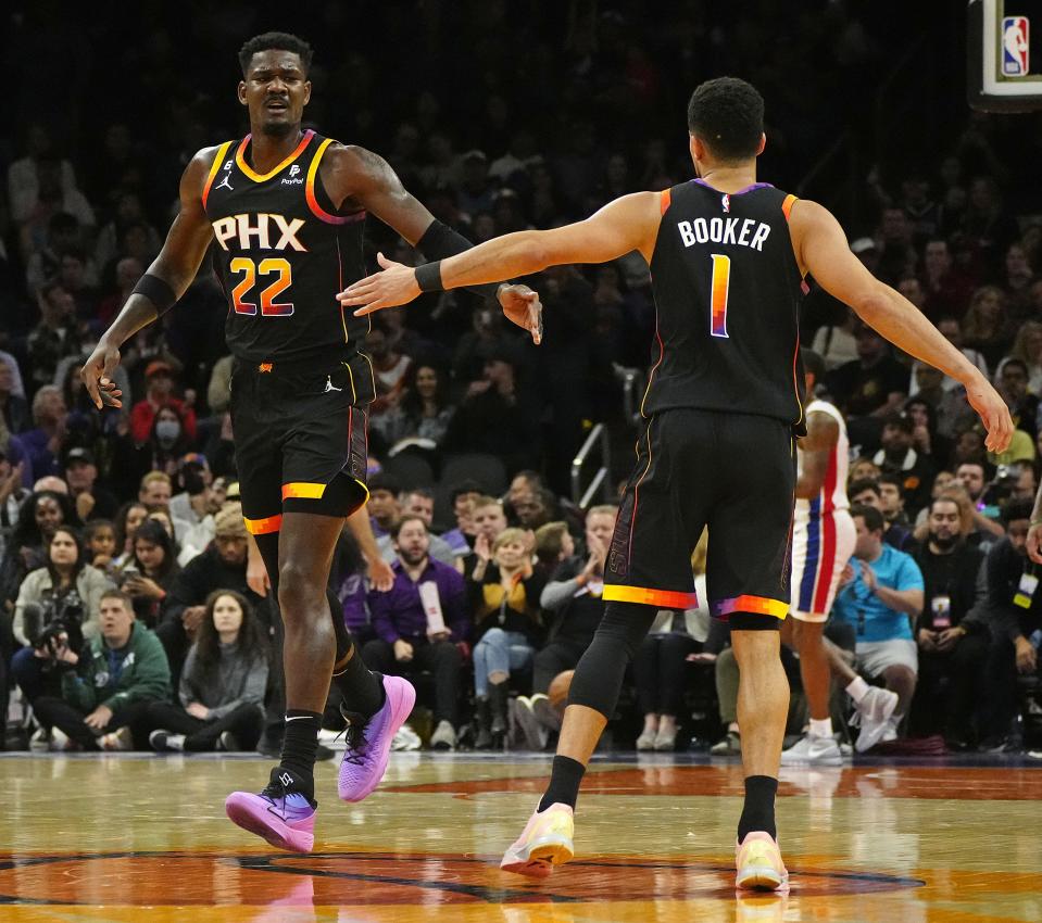 November 25, 2022; Phoenix, Ariz; USA; Suns guard Devin Booker (1) and center Deandre Ayton (22) celebrate a basket against the Pistons during a game at the Footprint Center.
