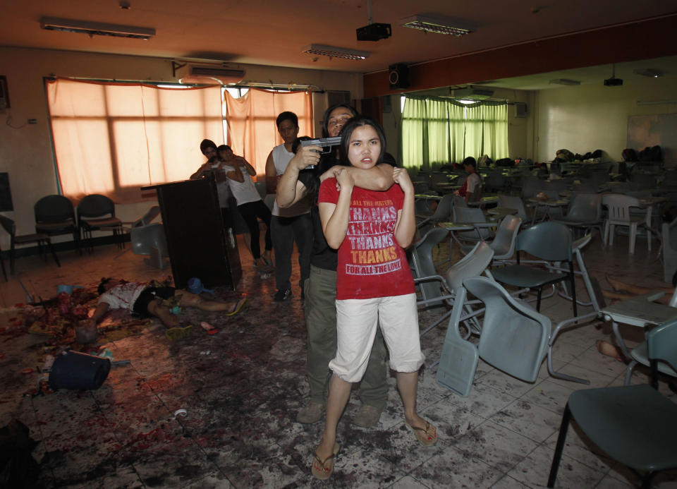 Mock terrorists hold mock victims at gunpoint as part of a mass casualty incident drill, in a university in Quezon City, Metro Manila