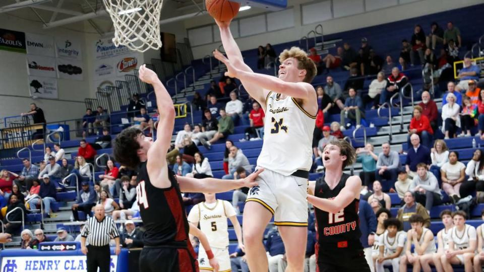 Sayre’s Ian Reesor (34) drives the baseline for a layup between Scott County’s Preston Luckett (24) and Ben Glenn (12) during their opening-round game in the boys 42nd District Tournament at Henry Clay High School on Monday.