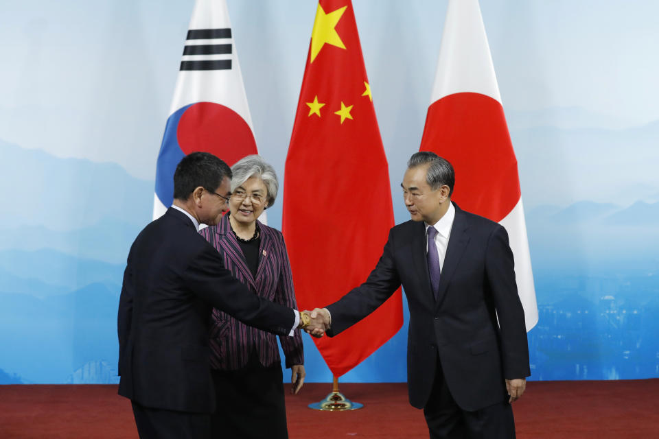 Chinese Foreign Minister Wang Yi, right, shakes hands with his Japanese counterpart Taro Kono, watched by South Korean counterpart Kang Kyung-wha, before their trilateral meeting at Gubei Town in Beijing Wednesday Aug. 21, 2019. (Wu Hong/Pool Photo via AP)