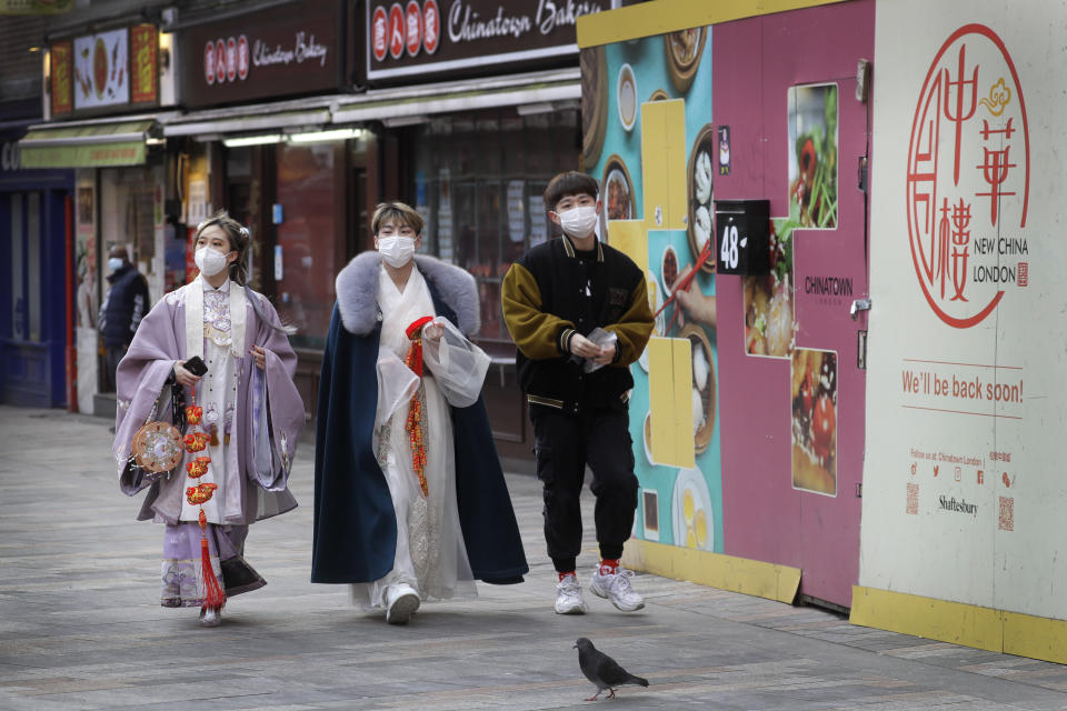 People wear traditional clothing as they walk through China Town in London, Thursday, Feb. 11, 2021. The Chinese New Year, which will be the Year of the Ox, will start on Friday, but due to the coronavirus pandemic many celebrations have been cancelled. (AP Photo/Kirsty Wigglesworth)