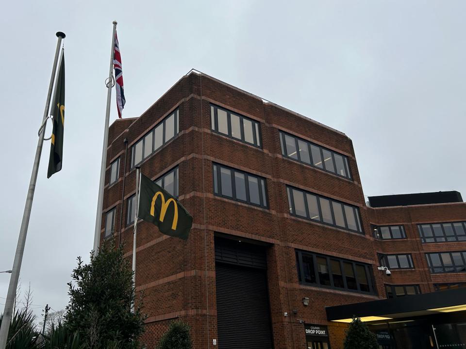 Une photo du siège social de McDonald's au Royaume-Uni, avec un drapeau McDonald's flottant devant le bâtiment.