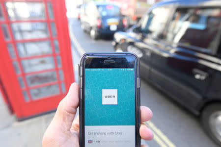 A photo illustration shows a London taxi passing as the Uber app logo is displayed on a mobile telephone, as it is held up for a posed photograph in central London September 22, 2017. REUTERS/Toby Melville