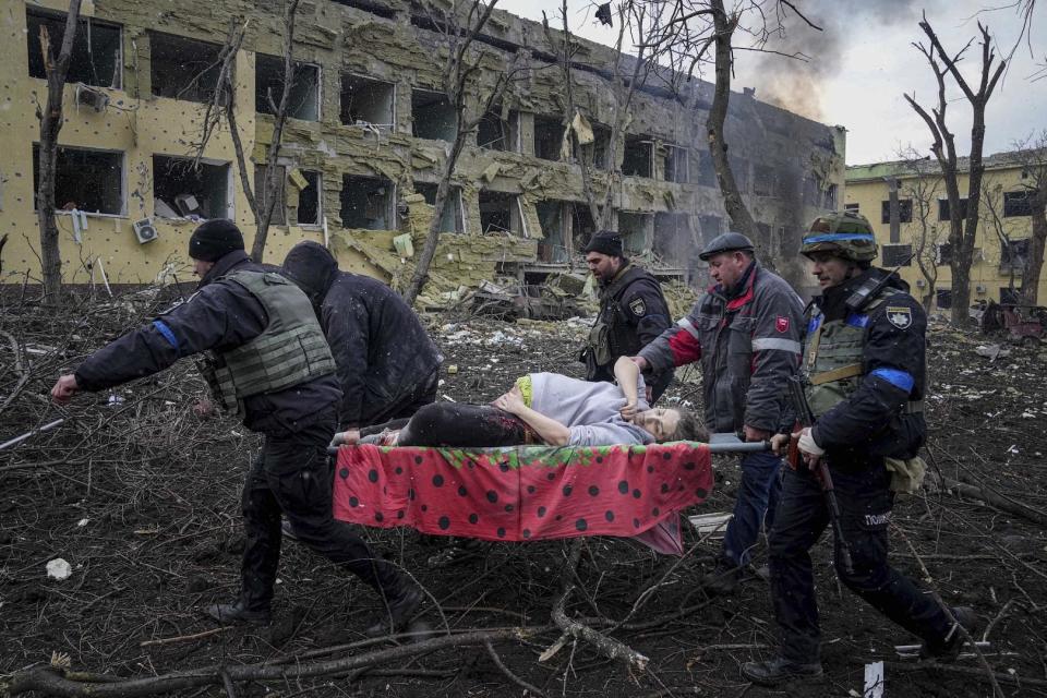 Ukrainische Rettungskräfte und Freiwillige tragen eine verletzte schwangere Frau aus einer Entbindungsklinik in Mariupol, 9. März 2022