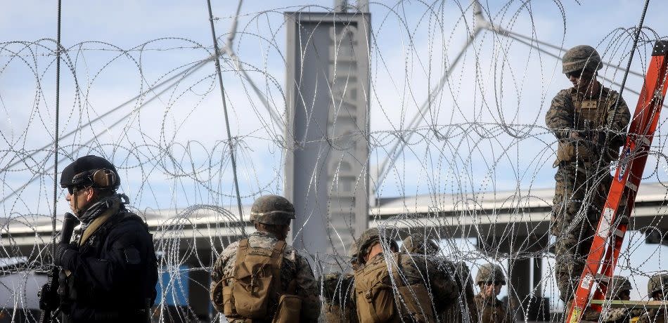 A U.S. Customs and Border Protection (CBP) agent (L) stands watch as U.S. troops set up concertina wire at the San Ysidro port of entry during a "large-scale operational readiness exercise" which briefly closed the border crossing on November 22, 2018 in Tijuana, Mexico.