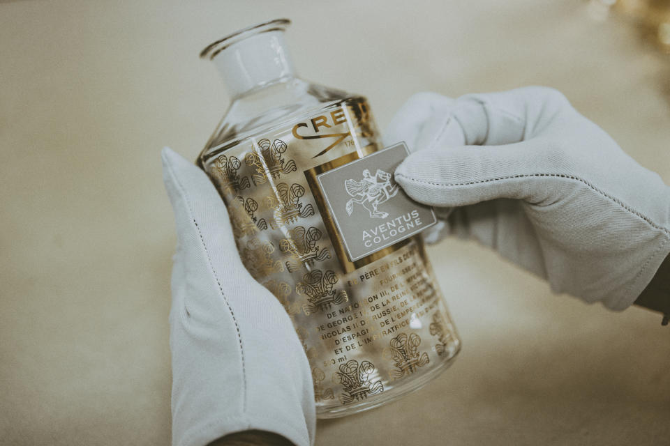 A worker applies a label to Aventus Cologne by Creed.