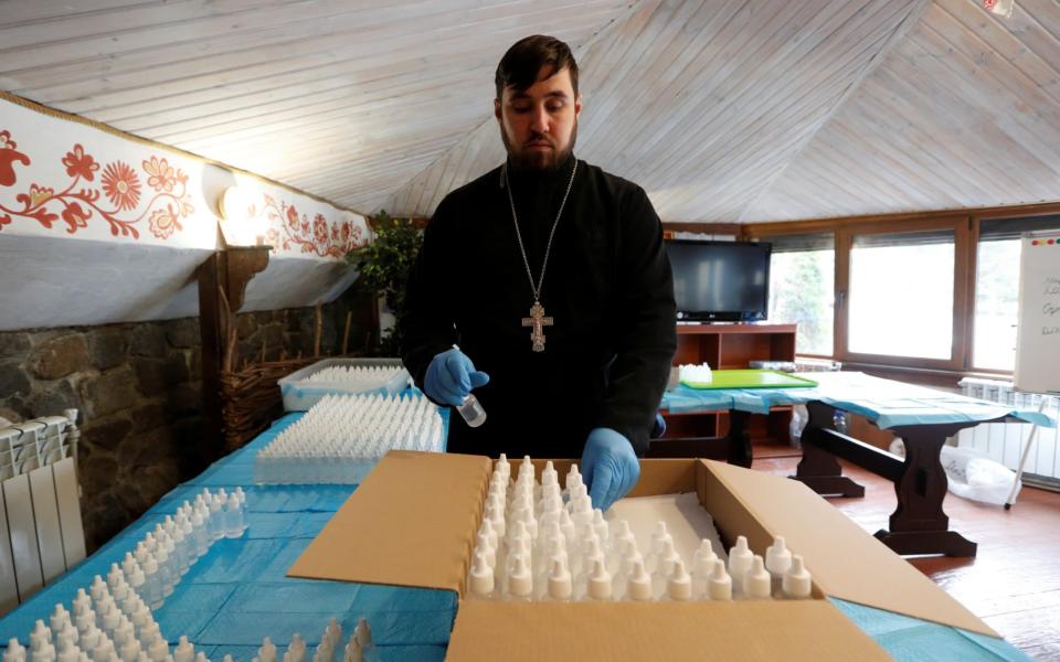 A clergyman of the Orthodox Church of Ukraine packs bottles of hand sanitizer at the Vydubychi Monastery in Kiev, Ukraine  - REUTERS