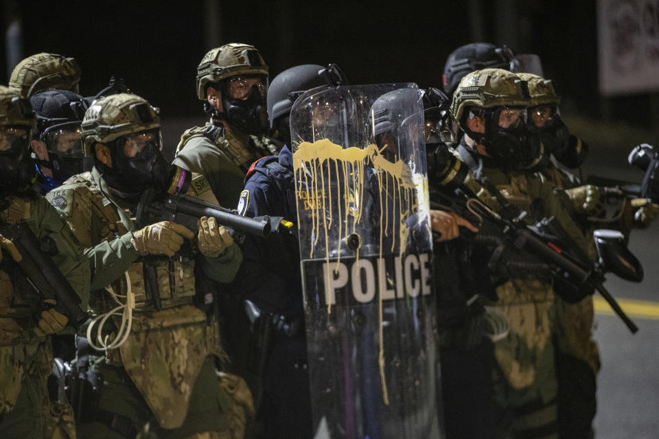 Police confront protesters outside the U.S. Immigration and Customs Enforcement office in Portland, Ore., Thursday, Aug. 20, 2020. Portland police say people in a group of about 100 late Thursday and early Friday sprayed the building with graffiti, hurled rocks and bottles at agents and shined laser lights at them.(Mark Graves /The Oregonian via AP)