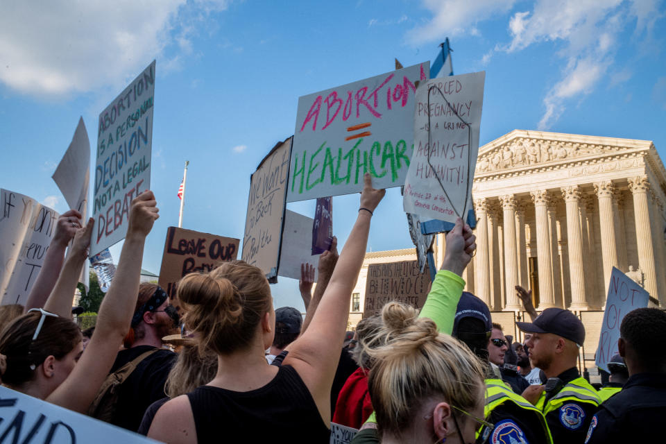 Protesters outside the Supreme Court holding up signs like "Abortion = healthcare"