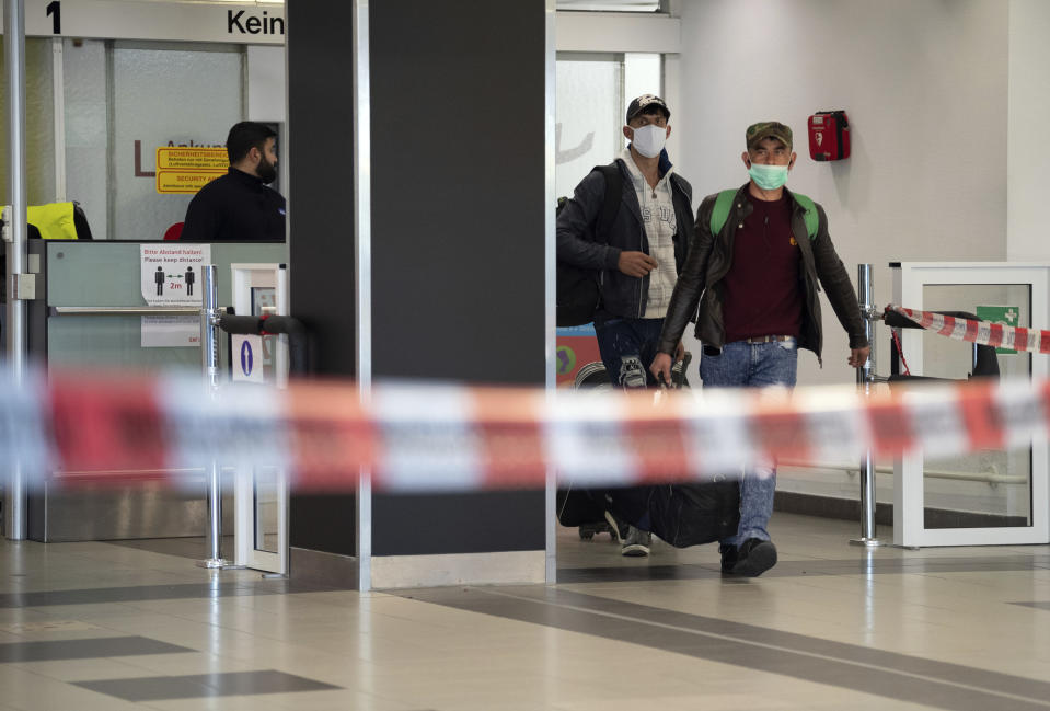 First people from Craiova in Romania arrive with their luggage and face masks at the 'Schoenefeld Airport' in Berlin, Germany, Thursday, April, 2020. The first planes with harvest workers from Romania have been landing in the morning. (Soeren Stache/dpa via AP)