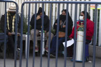 People wait to refill oxygen tanks for relatives sick with COVID-19 in the Iztapalapa district of Mexico City, on Tuesday, Jan. 26, 2021. The city is offering free oxygen refills for patients with COVID-19. (AP Photo/Marco Ugarte)