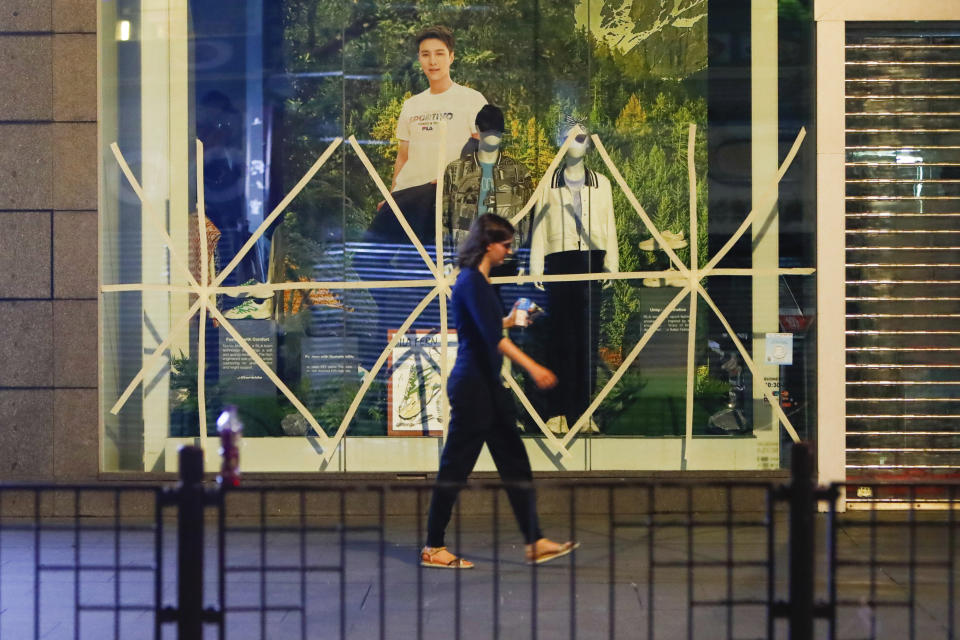 A woman walks past a fashion store with windows taped early in the morning, as a precaution against the approaching Super Typhoon Saola, in Hong Kong, on Friday, Sept. 1, 2023. The Hong Kong Observatory raised a No. 8 typhoon signal, the third-highest warning under the city's weather system, early Friday, and schools are suspended. (AP Photo/Daniel Ceng)