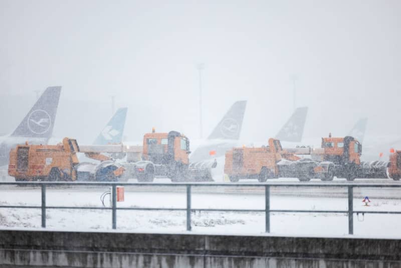 Snow clearing vehicles drive past parked airplanes at Frankfurt Airport after many flights were canceled due to bad weather conditions. Lando Hass/dpa