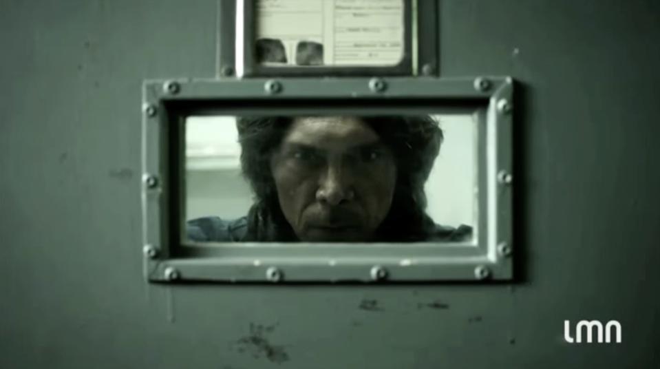 Movie still for the film "The Night Stalker" featuring Lou Diamond Phillips with a menacing face; he's looking through a small prison window