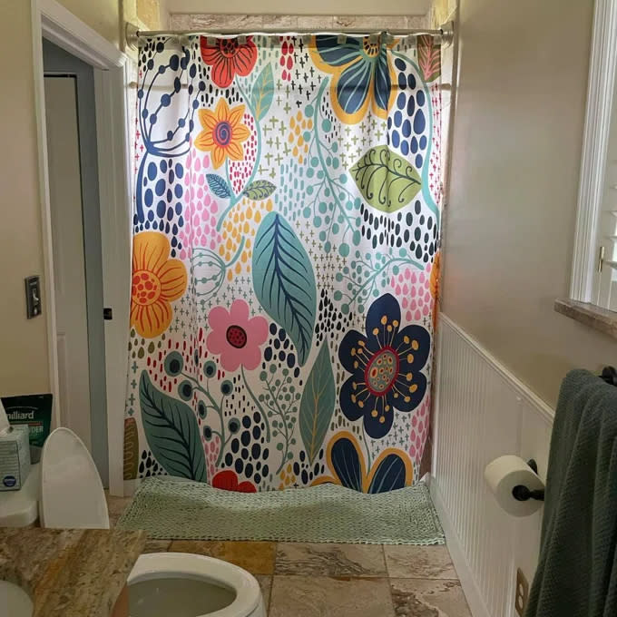Reviewer's photo of the vibrant floral pattern shower curtain inside a bathroom