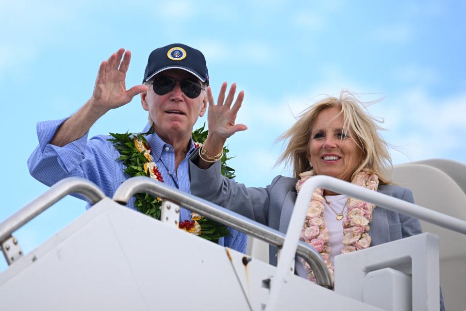 President Joe Biden and First Lady Jill Biden wear Hawaiian leis as they wave from Air Force One before departing Kahului Airport in Kahului, Hawaii, on Monday, Aug. 21, 2023. The Bidens spent the day meeting with first responders, survivors, and local officials following deadly wildfires in Maui.