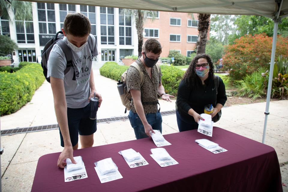 Florida State University students pick up packs of five free reusable face masks and a flyer with guidance for using them on the first day of classes for the fall semester in Landis Green Monday, August 24, 2020. 