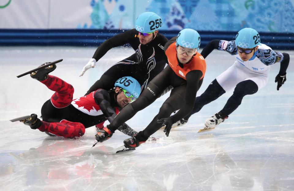 Charles Hamelin of Canada, left, crashes out with Eduardo Alvarez of the United States, second from left, as they compete with Sjinkie Knegt of Netherlands, second from right, and Victor An of Russia in a men's 1000m short track speedskating quarterfinal at the Iceberg Skating Palace during the 2014 Winter Olympics, Saturday, Feb. 15, 2014, in Sochi, Russia.