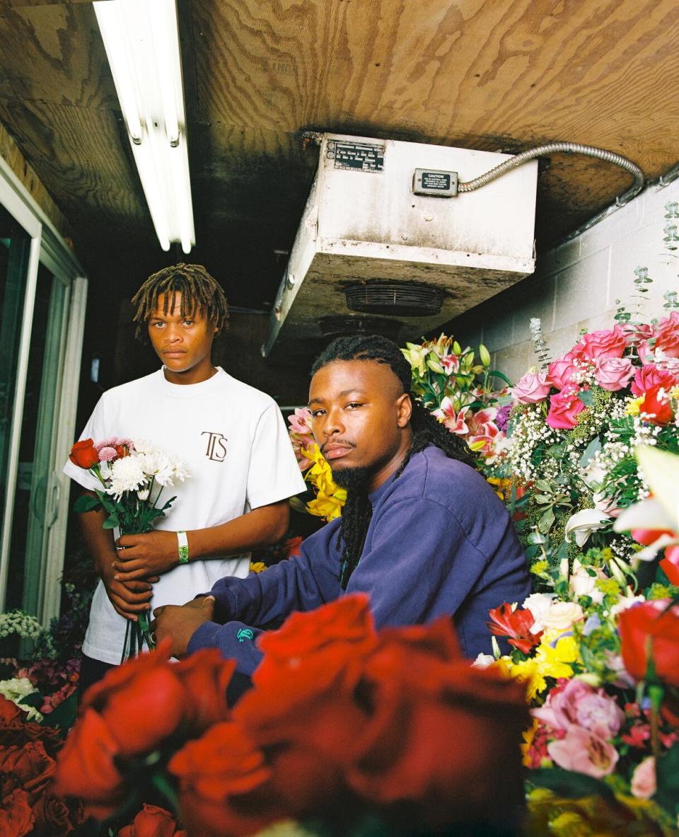 Two men sit inside a flower shop.