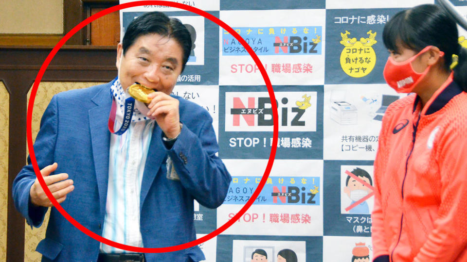 In this picture, Nagoya mayor Takashi Kawamura puts an athlete's gold medal in his mouth in a bizarre act.