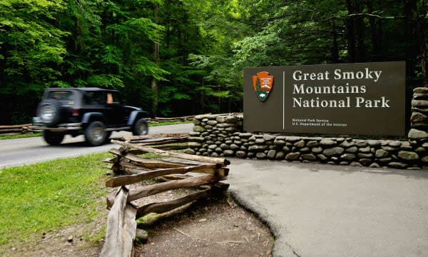 Jeep with Motion Blur Driving Past the Entrance Sign to the Great Smoky Mountains National Park on Route 441 in Tennessee