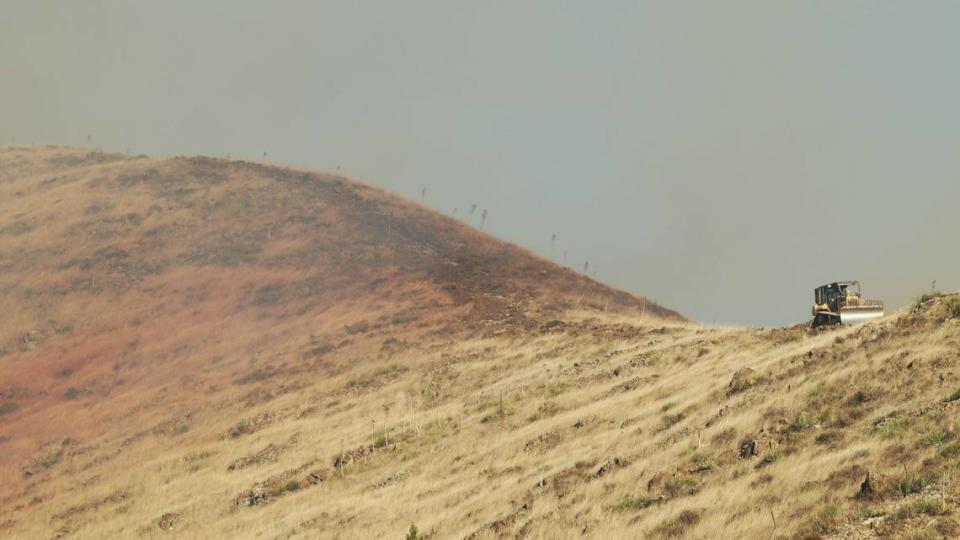 A bulldozer works a smoky ridgline above a vegetation fire that burned the hills near San Luis Obispo High School on Monday, Oct. 30, 2023.