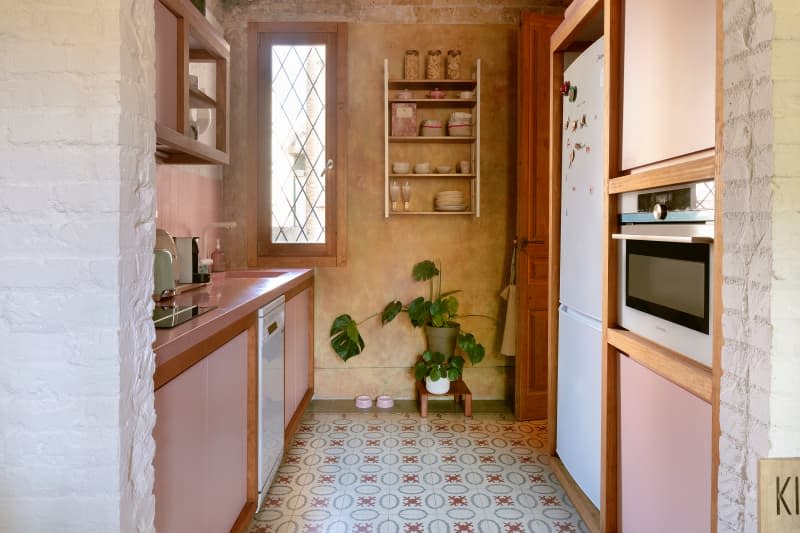 Pink cabinets in historic apartment with patterned tiles.