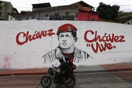 A motorcycle rides past a mural depicting late Venezuelan President Hugo Chavez, near his mausoleum in Caracas March 5, 2015. REUTERS/Jorge Silva