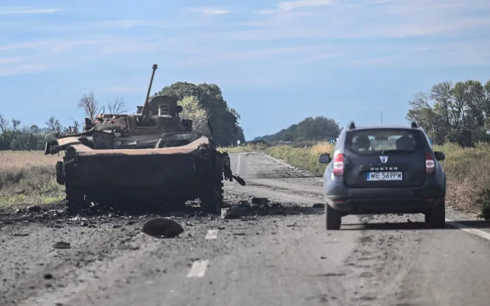  A car drives past a destroyed armored vehicle in Balakliya, Kharkiv region - JUAN BARRETO/AFP via Getty Images
