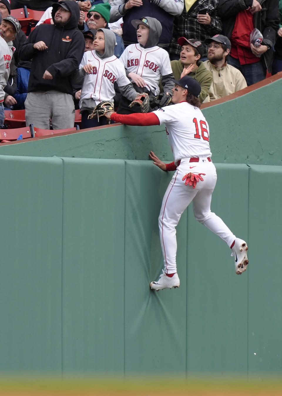 Boston Red Sox's Jarren Duran (16) leaps to the stands while reaching for a fly ball by Cleveland Guardians' Brayan Rocchio, that was foul, in the third inning of a baseball game, Thursday, April 18, 2024, in Boston. The ball (AP Photo/Steven Senne)
