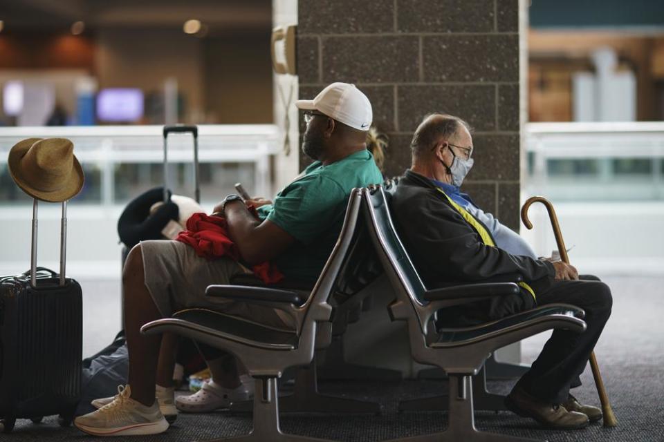 Travelers sit in a waiting area at Rhode Island T.F. Green International Airport in Providence, R.I., Tuesday, April 19, 2022. (AP Photo/David Goldman)