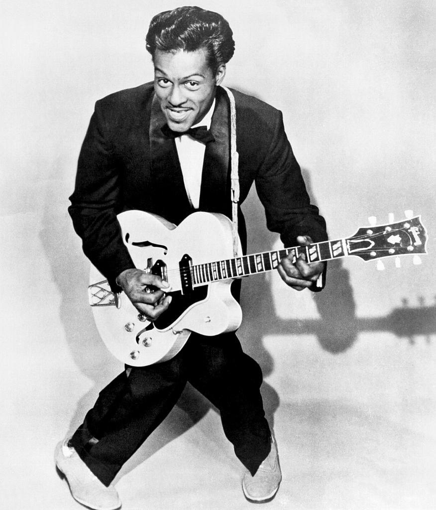 Berry posing for a portrait while playing his guitar in 1958