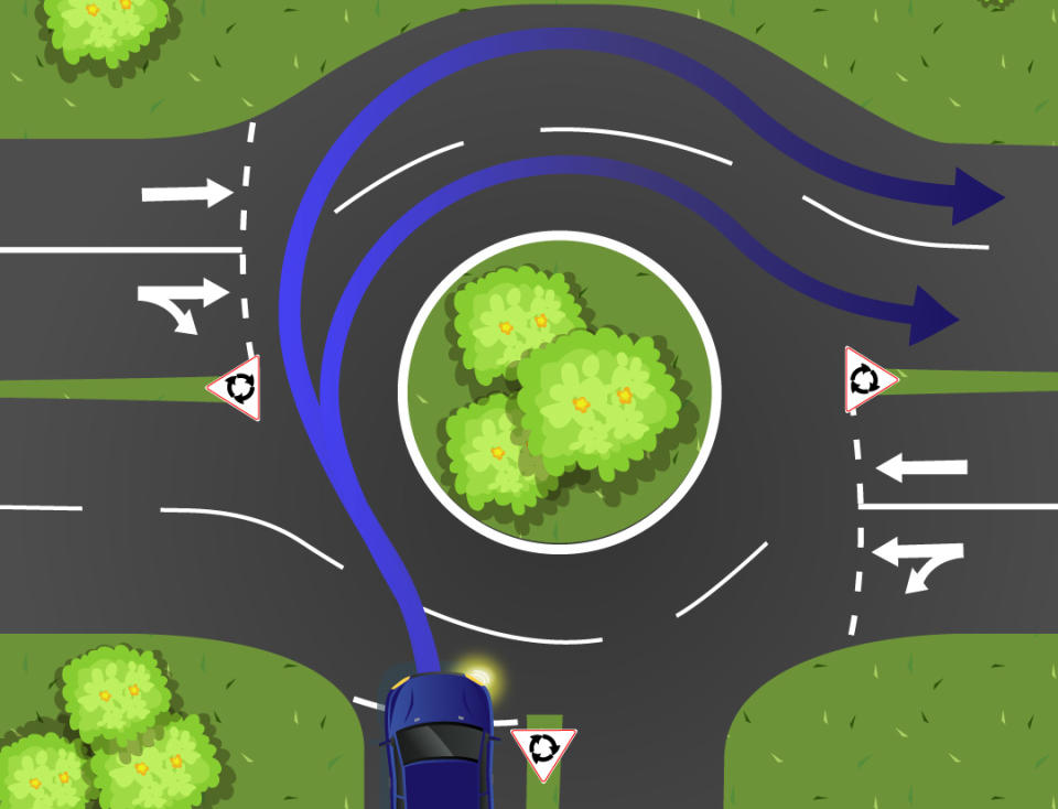 A blue car is pictured entering a two lane roundabout.