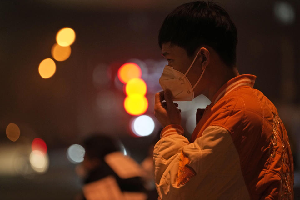 A man adjusts his mask on the street of Beijing, Sunday, Nov. 20, 2022. China on Sunday announced its first new death from COVID-19 in nearly half a year as strict new measures are imposed in Beijing and across the country to ward against new outbreaks. (AP Photo/Ng Han Guan)