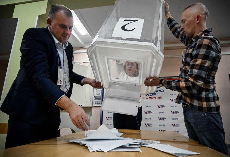 Los miembros de una comisión electoral local vacían una urna en un colegio electoral después del último día de las elecciones presidenciales de Rusia, que durarán tres días, en Moscú el 17 de marzo de 2024.