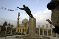 FILE - A U.S. marine watches a statue of Saddam Hussein being toppled in downtown Bagdhad Wednesday April 9, 2003. (AP Photo/Jerome Delay, File)