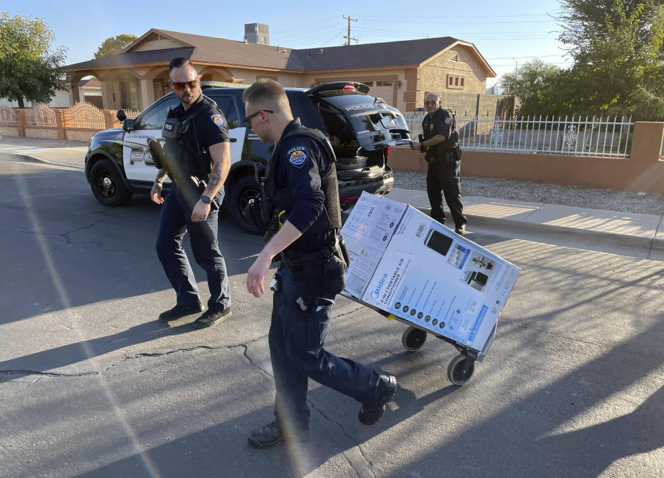 In this image provided by the Surprise, Ariz., Police Department, Surprise Police Department officers deliver an an air conditioner purchased for two elderly sisters, Paula Martinez, 93, and Linda Martinez, 87, they found sweltering inside their old home in 114 degrees F. (46 C.), Friday, July 14, 2023, in Surprise, Az. Efforts to protect older vulnerable people like the Martinez sisters during hot weather have increased in Arizona in recent years following the heat associated death five years ago of 72-year-old Stephanie Pullman in the Sun City West retirement community after her electricity company Friday, July 14, 2023, in Surprise, Ariz. (Surprise Police Department via AP)