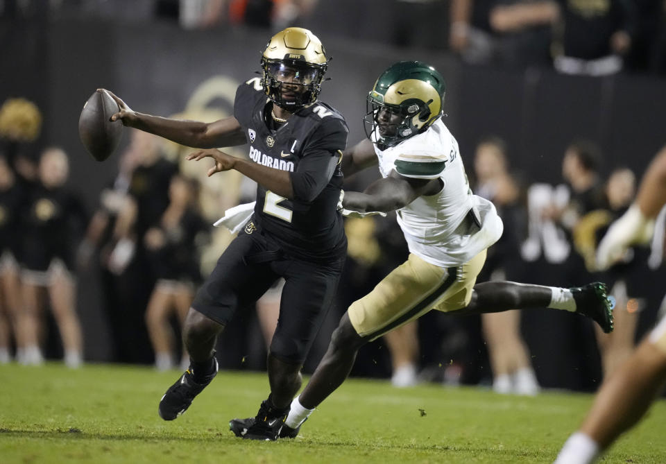 Colorado quarterback Shedeur Sanders, left, eludes a tackle by Colorado State defensive lineman Nuer Gatkuoth in the second half of an NCAA college football game Saturday, Sept. 16, 2023, in Boulder, Colo. (AP Photo/David Zalubowski)