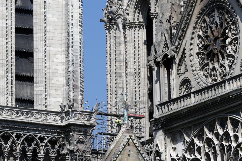 Workers prepare to remove a statue from the damaged Notre Dame cathedral, in Paris, Friday, April 19, 2019. Rebuilding Notre Dame, the 800-year-old Paris cathedral devastated by fire this week, will cost billions of dollars as architects, historians and artisans work to preserve the medieval landmark. (AP Photo/Thibault Camus)