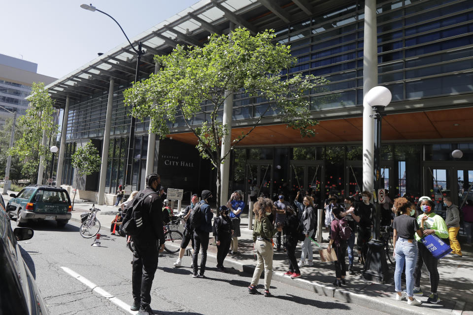 Protesters block a street in front of Seattle City Hall, Monday, July 13, 2020, following a news conference where Police Chief Carmen Best and Mayor Jenny Durkan spoke critically about a plan backed by several city council members that seeks to cut the police department's budget by 50 percent. (AP Photo/Ted S. Warren)