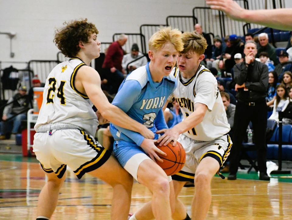 York’s Derek Parsons, center, is fouled as he splits Medomak Valley’s Luke Cheesman, left, and Jaiden Starr during the Class B South quarterfinals Friday at the Portland Expo.