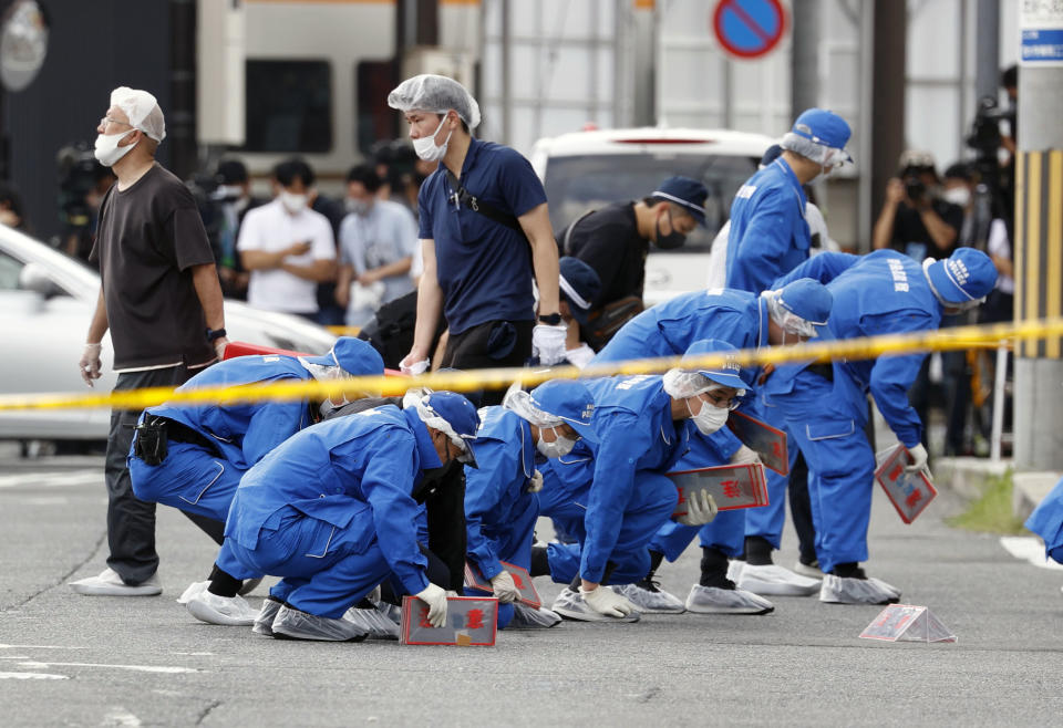 Police inspect the site where Japanese former Prime Minister Shinzo Abe was fatally shot in Nara, western Japan, July 8, 2022. Many people mourned the death of Abe at the site where he was gunned down during a campaign speech a week ago Friday, shocking a nation known for its low crime rate and strict gun control. (Kyodo News via AP)