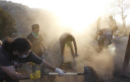 Residents remove debris from their burned house after a fire burned several neighbourhoods in the hills in Valparaiso city, northwest of Santiago, April 14, 2014. REUTERS/Eliseo Fernandez