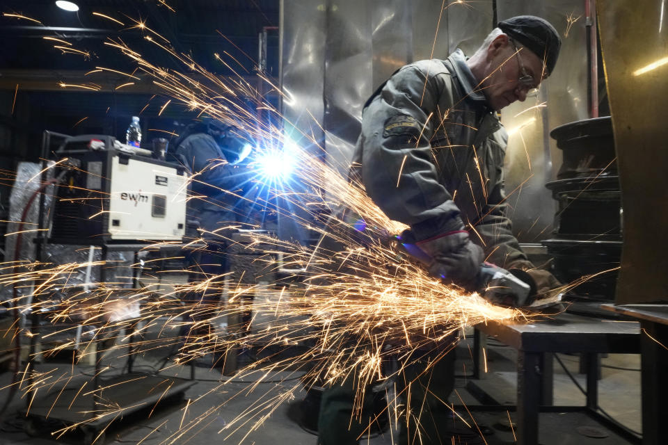 A volunteer welds a heating stove from old car rims in workshop in Siauliai, some 230 km (144 miles) north-west of the capital Vilnius, Lithuania, Thursday, Feb. 2, 2023. In a dusty workshop in northern Lithuania, a dozen men transform hundreds of wheel rims into potbelly stoves to warm Ukrainians huddled in trenches and bomb shelters. (AP Photo/Sergei Grits)