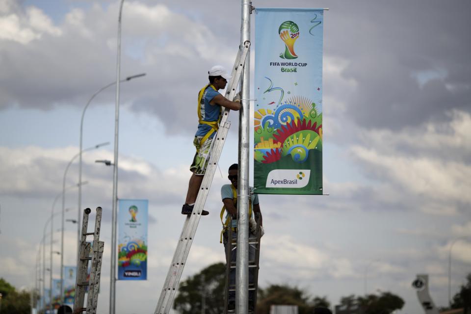 Men hang a World Cup poster at a street near Mane Garrincha National Stadium, one of the venues for the upcoming World Cup, in Brasilia. (Ueslei Marcelino/Reuters)