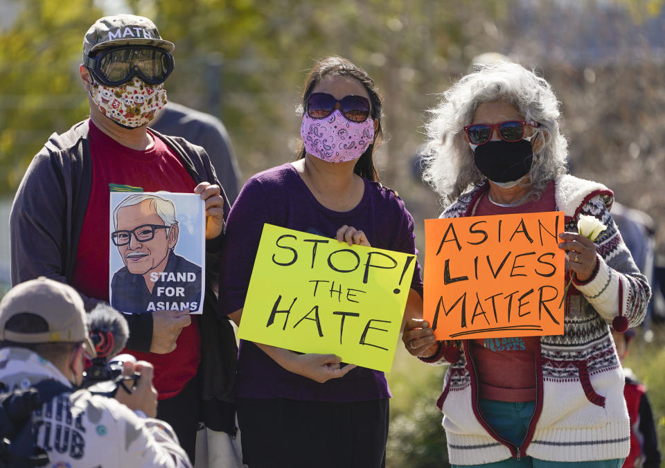 A man holds a portrait of late Vichar Ratanapakdee, left, a 84-year-old immigrant from Thailand, who was violently shoved to the ground in a deadly attack in San Francisco, during a community rally to raise awareness of anti-Asian violence and racist attitudes, in response to the string of violent racist attacks against Asians during the pandemic, held at Los Angeles Historic Park near the Chinatown district in Los Angeles, Saturday, Feb. 20, 2021. (AP Photo/Damian Dovarganes)