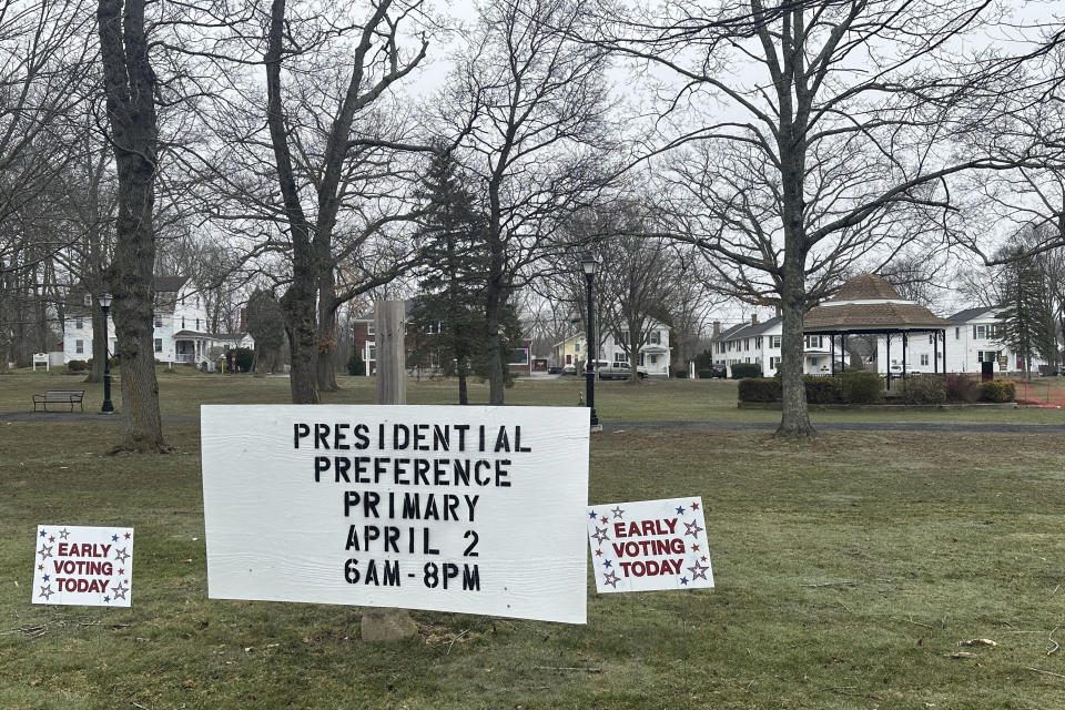 Signs dot the town green in Colchester, Conn., on Wednesday, March 27, 2024, reminding voters they can vote early in the state's presidential primary. It marks the first time voters can vote early and in-person in Connecticut. (AP Photo/Susan Haigh)